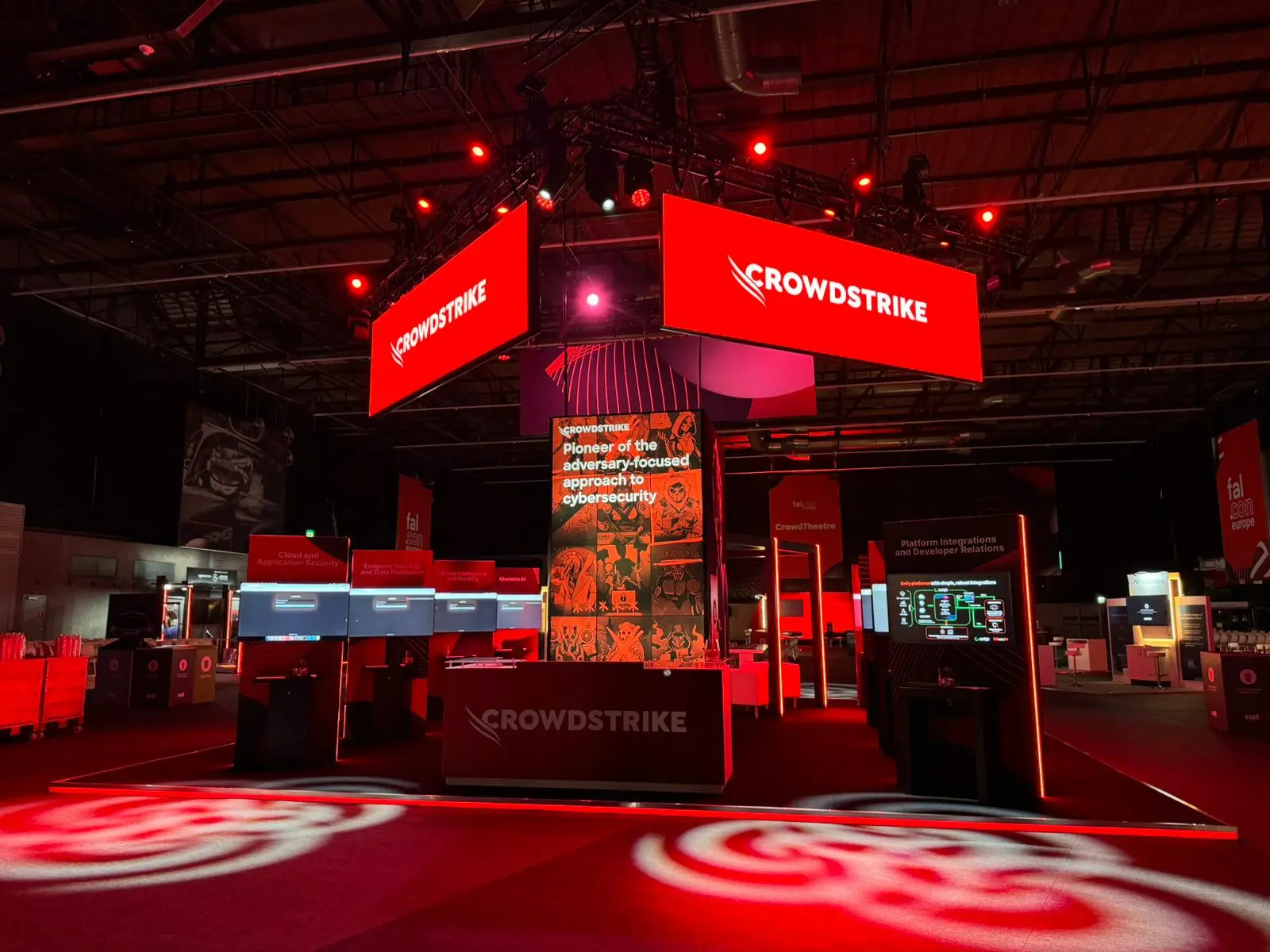 Suspended LED screens and totem displays above a technology exhibition booth